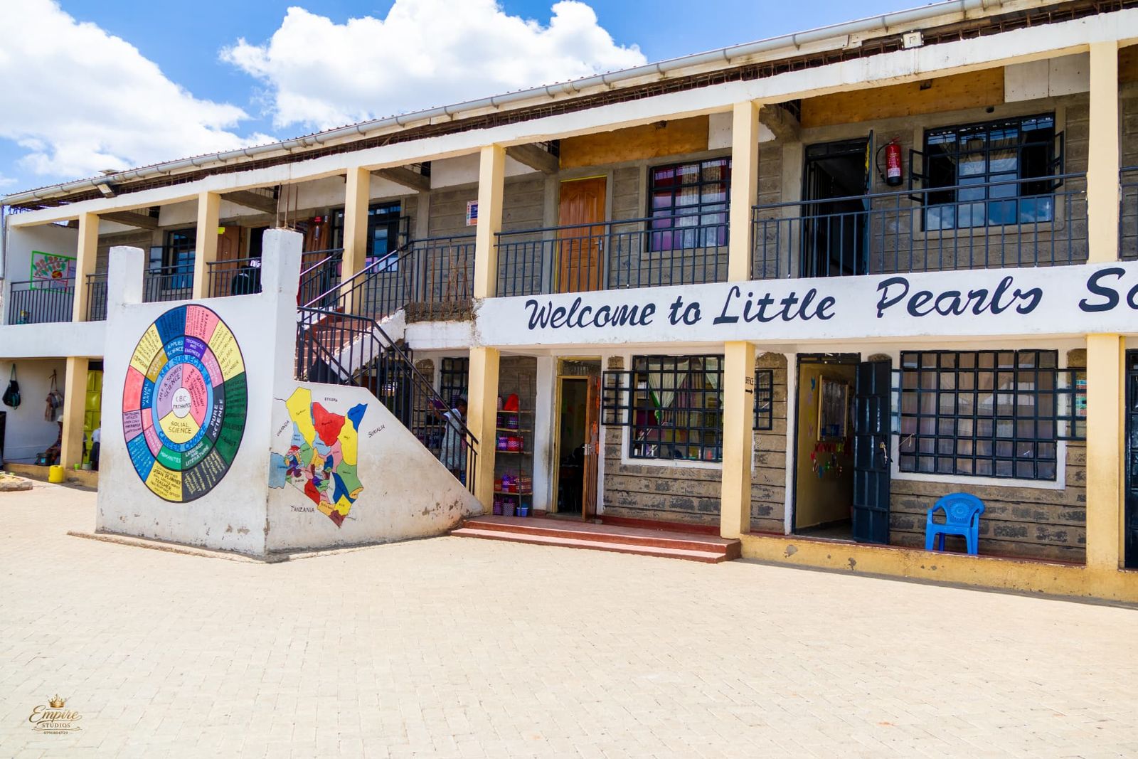 The two-storey Little Pearls School building with its 'Welcome to Little Pearls School' sign, CBC pathways wheel and map of Kenya